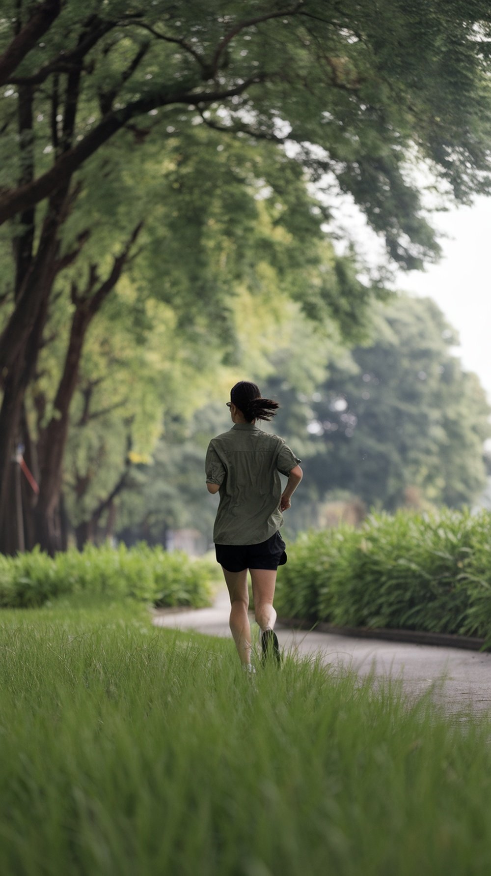 A person jogging on a green path surrounded by trees.